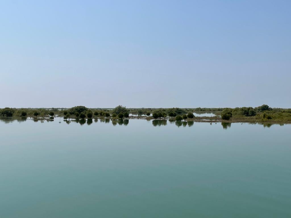 A blue landscape picture showing the calm waters off of Karachi, Pakistan and the cloudless blue sky above.